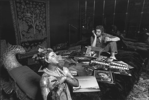 Gainsbourg sur son lit, entouré de quelques-uns de ses albums souvent illustrés par des photos de Tony Frank, 1979